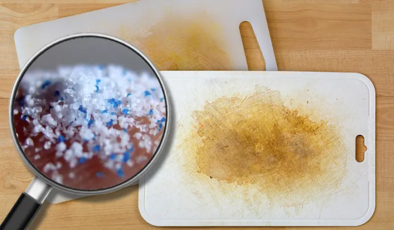 Stained plastic cutting boards with a magnifying glass over surface debris.